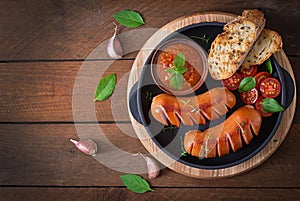 Sausages on the grill with vegetables. Top view