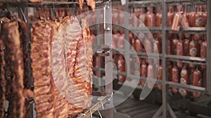 Sausages, grilled ribs, meat products at a storage rack in a food factory. Dolly shot.