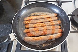 Sausages grilling in a frying pan