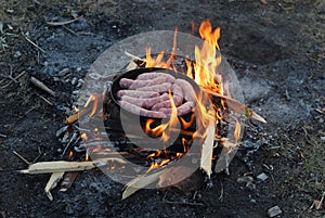 Sausages grilling over the hot glowing coals