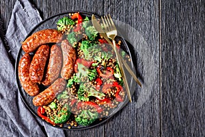 Sausages with lentils on a black plate, copy space