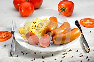 Sausages with pasta and tomatoes on a plate