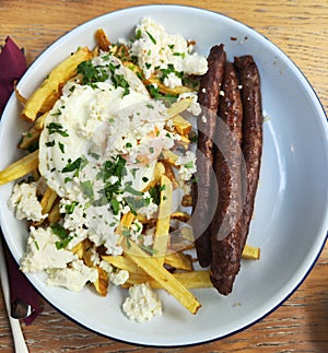 Sausages with poached eggs and fried potatoes with cheese