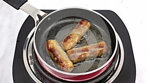 Sausages sizzling in frying pan