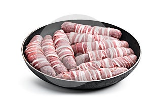 Sausages wrapped in bacon in frying pan isolated on white background