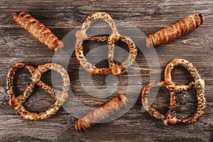 Sausages wrapped in puff pastry. Sausages in a dough and pretzels with seeds on a wooden background