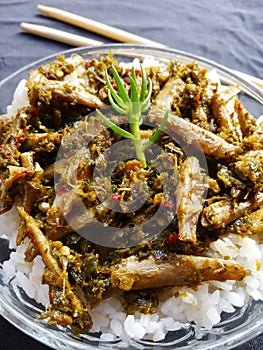 Sauteed anchovies cooked with green chili sauce, served in a bowl with rice.