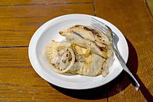 Sauteed pirogi with onions on a white plate