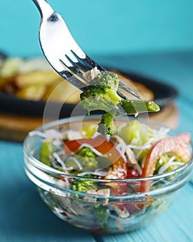 Sauteed vegetable salad with broccoli, asparagus, sweet pepper and cellophane noodles or fensi noodles in a glass bowl