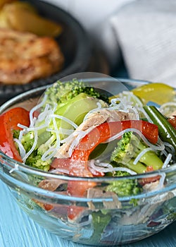 Sauteed vegetable salad with broccoli, asparagus, sweet pepper and cellophane noodles or fensi noodles in a glass bowl