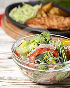 Sauteed vegetable salad with broccoli, asparagus, sweet pepper and cellophane noodles or fensi noodles in a glass bowl