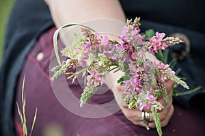 Savage flowers bouquet in hand of woman in a meadow