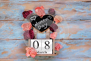 Save the date block calendar for International Womens day, March 8, with chalkboard, next to roses flowers, on blue