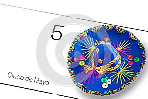 Save the date white calendar for Cinco de Mayo, May 5th with blue sombrero decorated with colorful sequins and golden. Cinco de