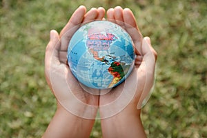 Save The Earth and Care Environment Concept, Close-up of Woman Hands is Holding Mockup Global Against on Tree Leave Background.