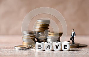 Save money concept, businessmen stand on money coin and save block word Save money for investment