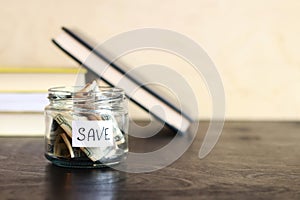 Save money for the future. Glass jar with dollars on a wooden table on the background of books. Piggy bank with banknotes, copy