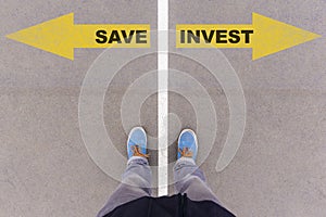 Save vs Invest text arrows on asphalt ground, feet and shoes on