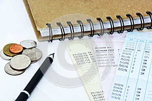 Saving account passbooks and coins with pen and notebook on white background