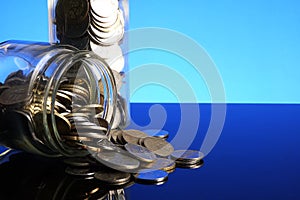 Saving concept with coins in a mason jar on a blue background. C