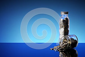 Saving concept with coins in a mason jar on a blue background. C