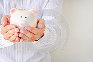 Saving Concept Image. Business Man holding a piggy bank with piggy bank in outstretched hand