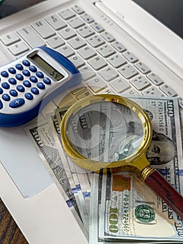 Saving concept magnifying glass with calculator and us dollar on laptop