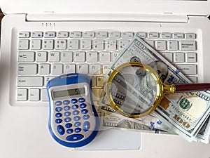 Saving concept magnifying glass with calculator and us dollar on laptop