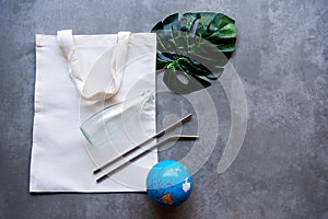 Saving Earth. White tote bag canvas package and fabric cloth eco shopping with Stainless tube, glass bottle on blackboard backgrou