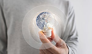 Saving energy, and earth day concept. a man holding glowing earth light bulb. Element of this image are furnished by NASA