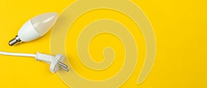 Saving energy, eco concept. LED light bulb and electrical power cable, yellow background, banner, top view and flat lay