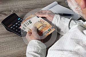 Saving, finance, economy and housing concept - close up of man with calculator counting money and making notes at home