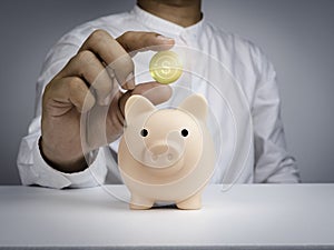 Saving and investment concept. Pink piggy bank and businessman`s hand in white shirt is holding and showing shining golden money.
