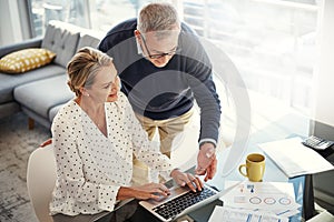 Saving keeps their retirement secure. a mature couple using a laptop while going through paperwork at home.