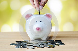 Saving, male hand putting a coin into piggy bank and money