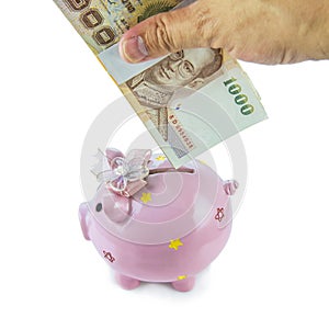 Saving, male hand putting a money into piggy bank isolated on white background