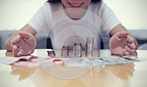 Saving money concept of Asian woman hand Protecting stack of coin on desk in office background