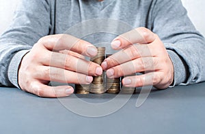 Saving money concept. Coins and male hands close up on a measured background