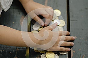 Saving money concept, crop hand on coins over wooden background