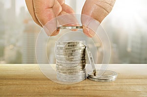 Saving money concept. hand putting coin to stacks of coins.