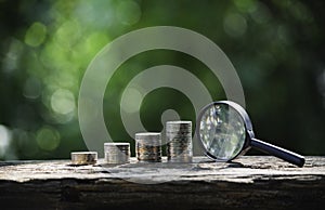 Saving money concept with money coin stack and magnifying glass. Financial and accounting concept