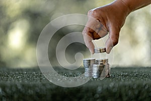 Saving money concept preset by female hand putting money coin stack growing business. Asian woman making stack of coin, planning