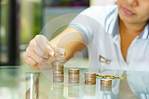 Saving money concept, woman stacking coins into increasing stack columns