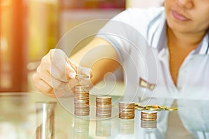 Saving money concepts, woman stacking coins into increasing columns