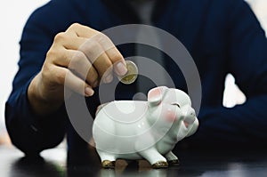 Saving money drops the piggy bank for investment or buying a fund or using it in an emergency. Men`s hands are dropping money at