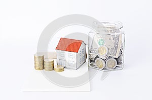 Saving money with Glass bottles and paper house and coins stack