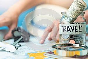 Saving money in a glass jar for travel on map