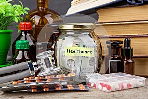 Saving money for health care insurance - money glass, stethoscope, pills and bottles