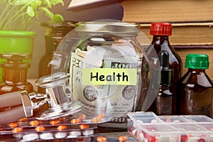 Saving money for health care insurance - money glass, stethoscope, pills and bottles