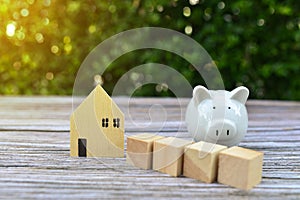 Saving money and home loans,saving for a real estate concept,Present by piggy bank ,home and wood cube with sunlight effect.